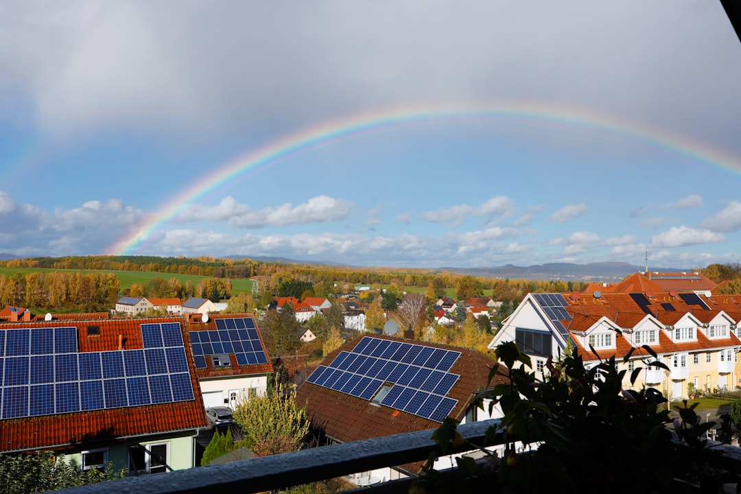 Homes under a rainbow sky with solar panels, representing the Bloomington community solar program's savings