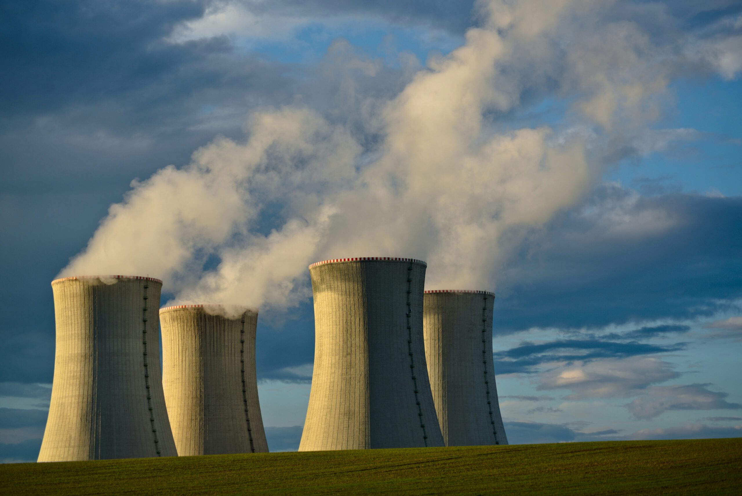 Concrete cooling towers at a uranium enrichment plant under a bright sky