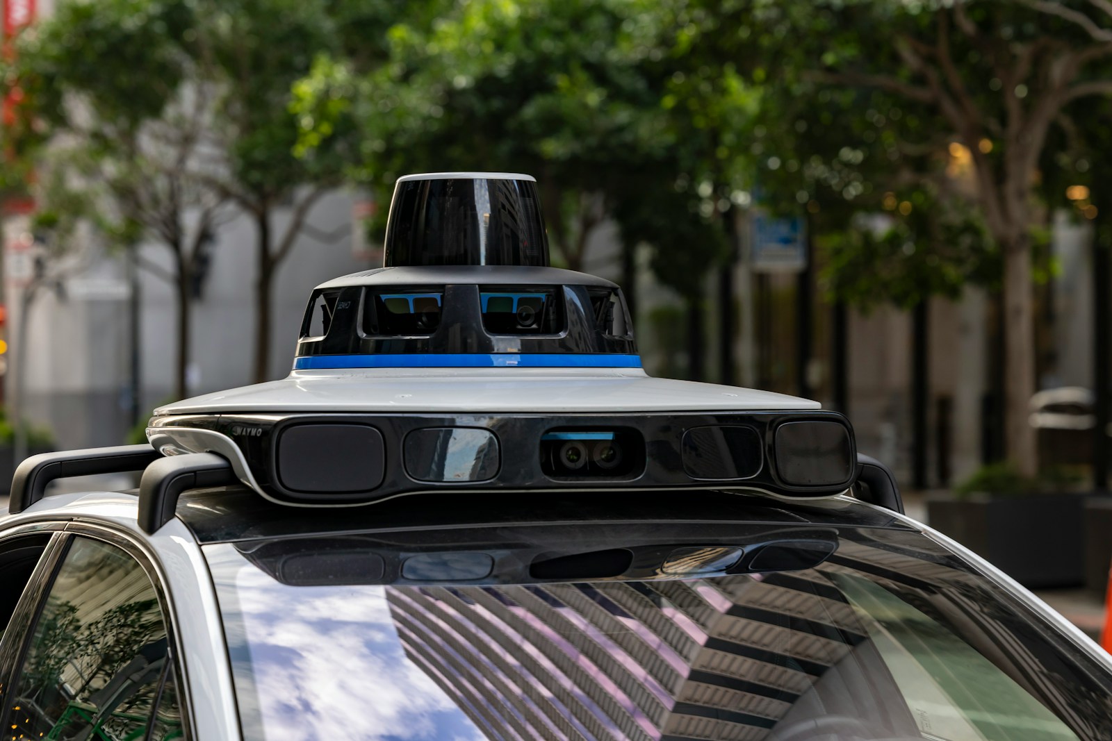 Self-driving car with sensors on a city street, representing the Waymo Denver robotaxi service