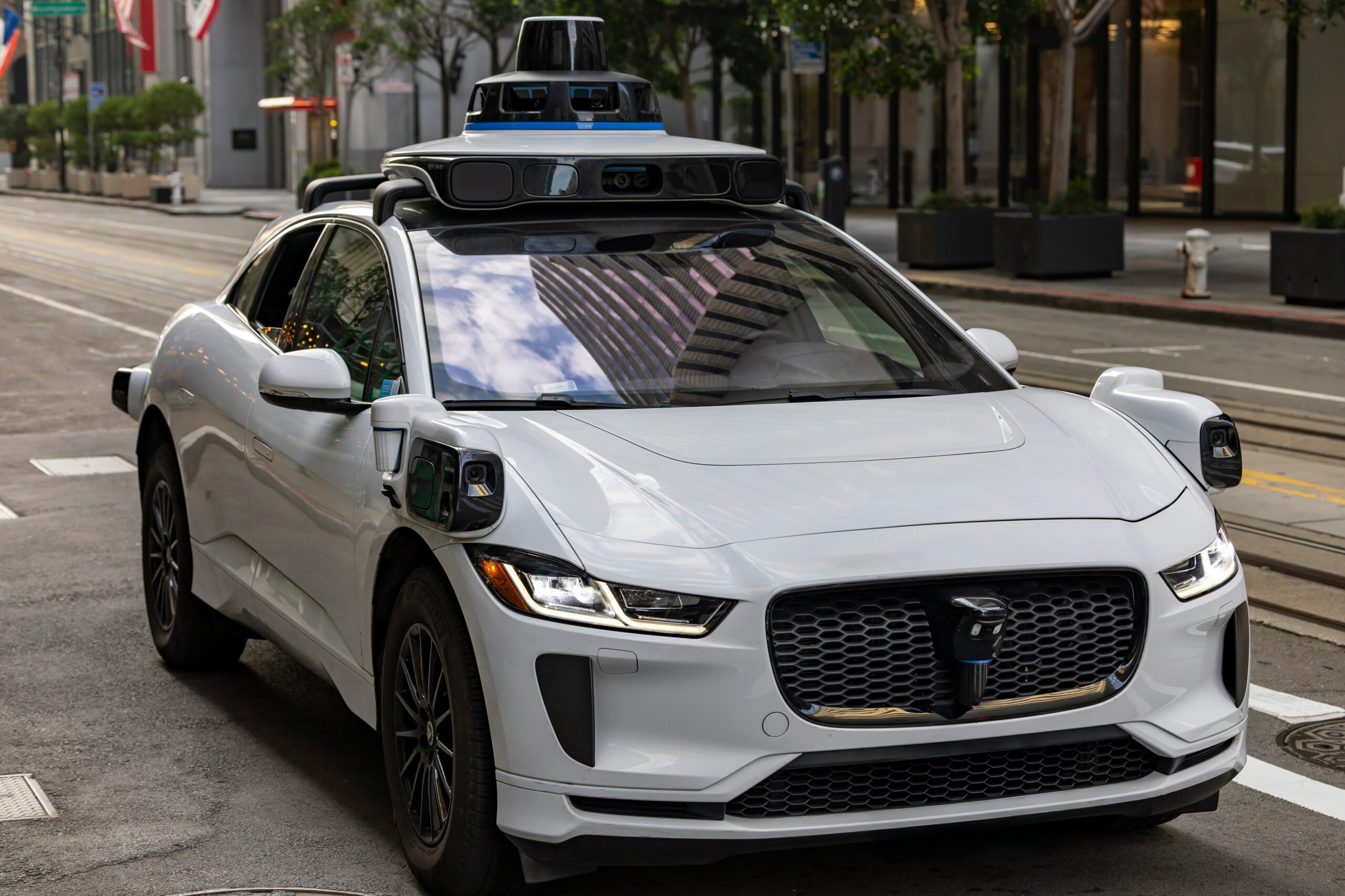 White self-driving car on a city street, representing the Waymo robotaxi San Diego launch
