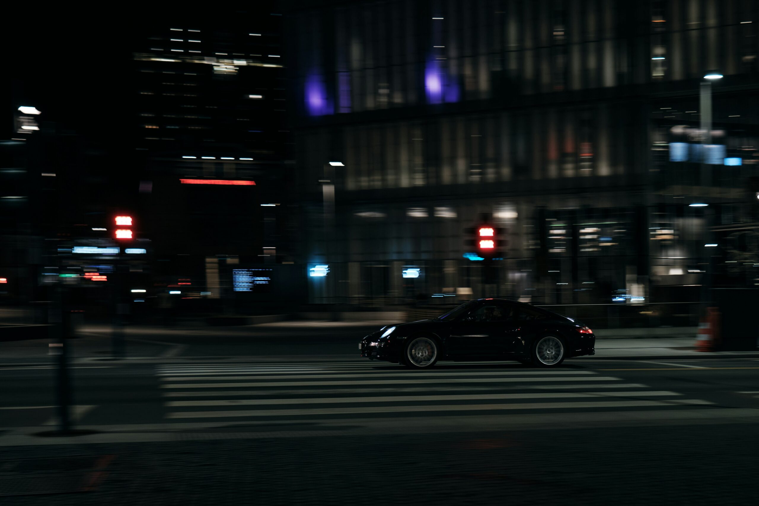 Autonomous car crossing a lit city street at night, symbolizing Zoox robotaxi safety after dark