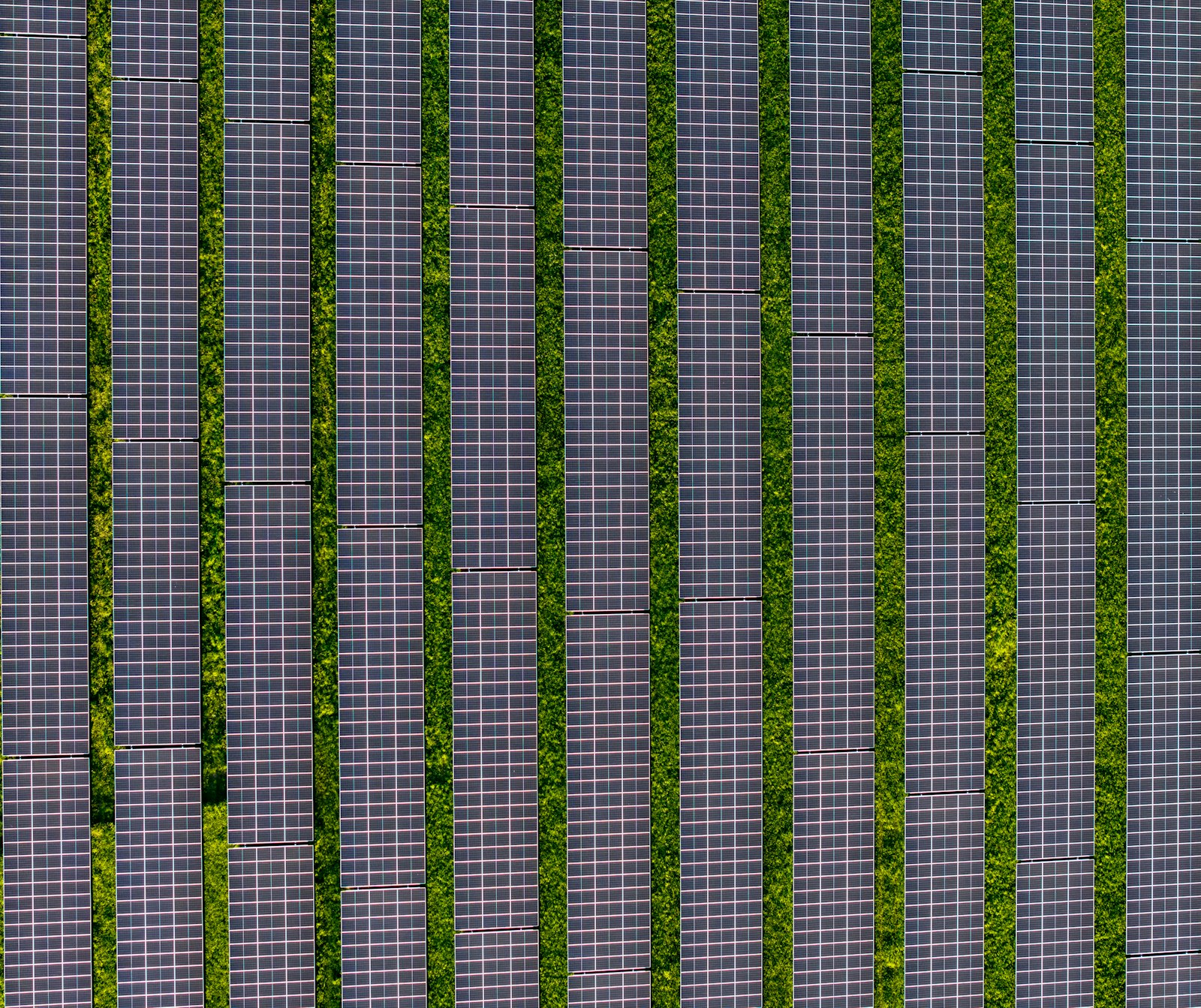 Aerial view of ground-mounted solar panel rows on grass, the kind of array planned for the Voorhees, New Jersey landfill