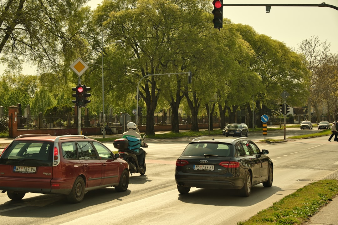 Cars stopped at a city intersection where rest-in-red traffic signals now reward safe, steady driving speeds.