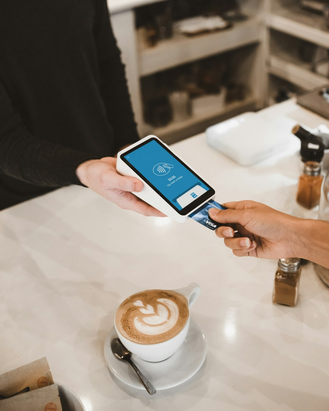 Person paying with a card at a payment terminal, symbolizing new stablecoin debit cards for everyday spending