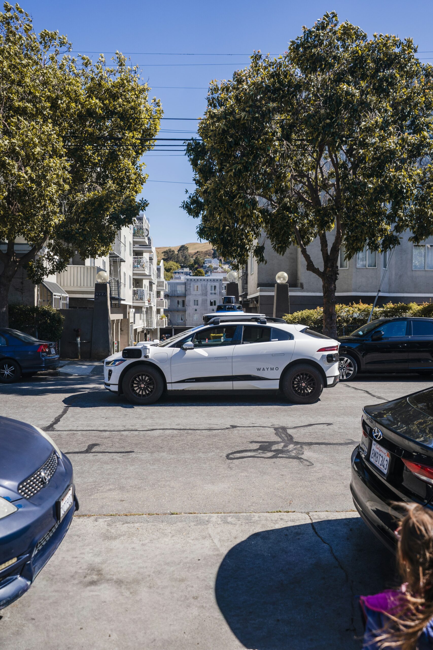 White self-driving car on a city street, illustrating Waymo's Texas robotaxi expansion