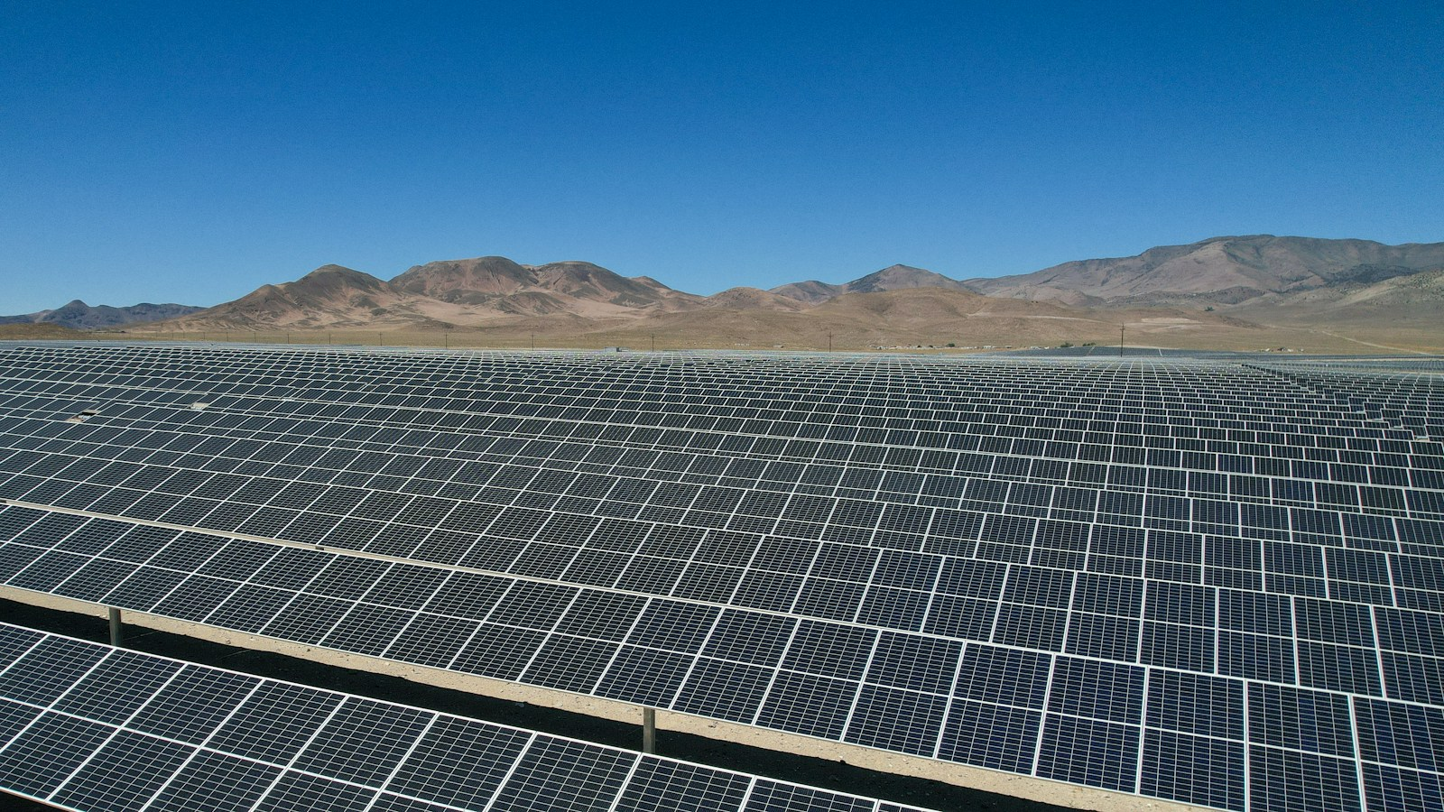 Rows of solar panels spread across a desert landscape, where Arizona added record battery storage