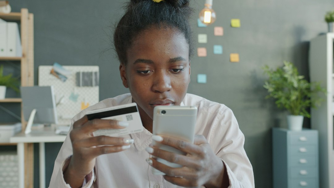 Woman smiling while using her smartphone for a digital payment, reflecting Kora stablecoin payments for everyday transactions