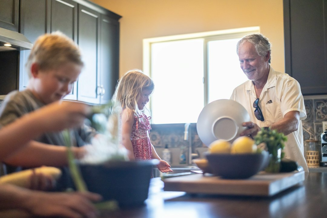 Grandfather and grandchildren cooking in a kitchen, representing the shared household Apple HomeView is built for